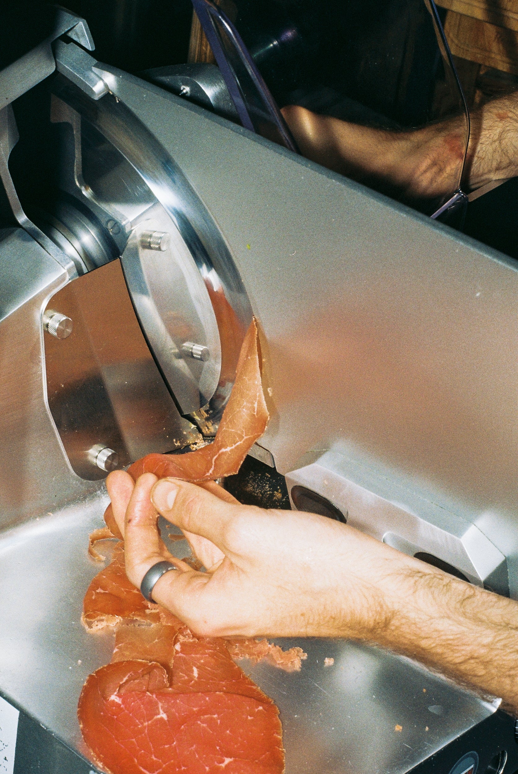 Hand using a meat slicer to cut slices of meat